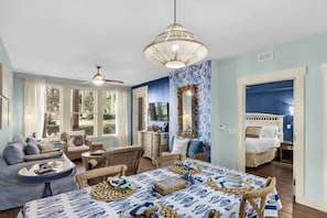 A room with a dining table set with wooden coasters, a ceiling fan, and a large mirror.