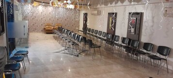 A room with rows of chairs and a long table, likely for a meeting or event.