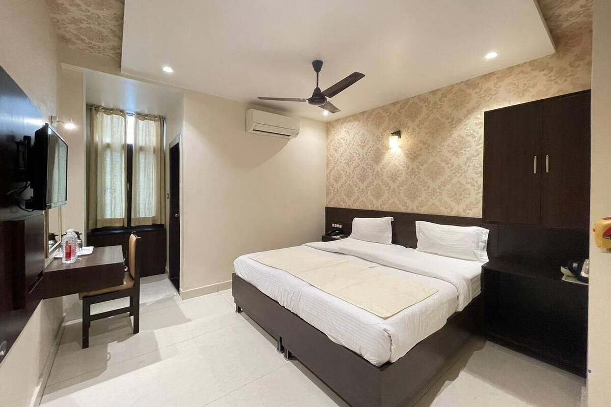Une chambre d’hôtel équipée d’un lit, d’un bureau, d’une chaise, d’une télévision, d’un ventilateur de plafond et d’une armoire.