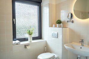 A modern bathroom with a toilet, sink, and a window with a view of the street. - 7Seas Apartment mit Balkon (Kaiserslautern)