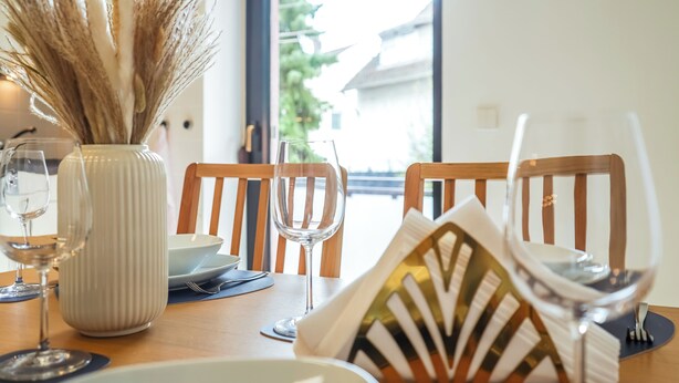 A dining table with a vase of dried pampas grass, two wine glasses, and a decorative pillow. - 7Seas Apartment mit Balkon (Kaiserslautern)