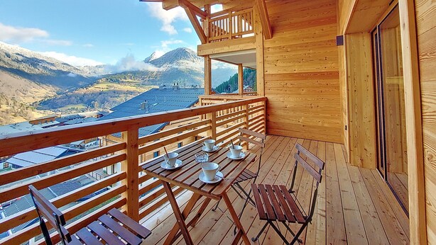 A wooden deck with a table set for dining, overlooking a mountainous landscape. - Snow Roc - 6/8 persons - Ski to door access - Mountain view (Saint-Jean-d´Aulps)