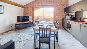 A modern kitchen with a dining area, wooden ceiling, and a view of mountains. - Snow Roc - 6/8 persons - Ski to door access - Mountain view (Saint-Jean-d´Aulps)