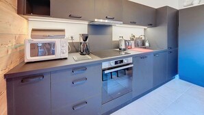 A modern kitchen with grey cabinets, a built-in microwave, a coffee maker, and a kettle. - Snow Roc - 6/8 persons - Ski to door access - Mountain view (Saint-Jean-d´Aulps)