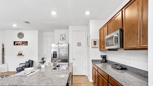 A modern kitchen with granite countertops, wooden cabinets, stainless steel appliances, and a central island.