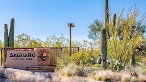 The entrance to Saguaro National Park with a signboard, a solar panel, and cacti.