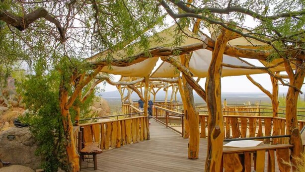 A wooden boardwalk with a canopy structure, leading to a scenic overlook.