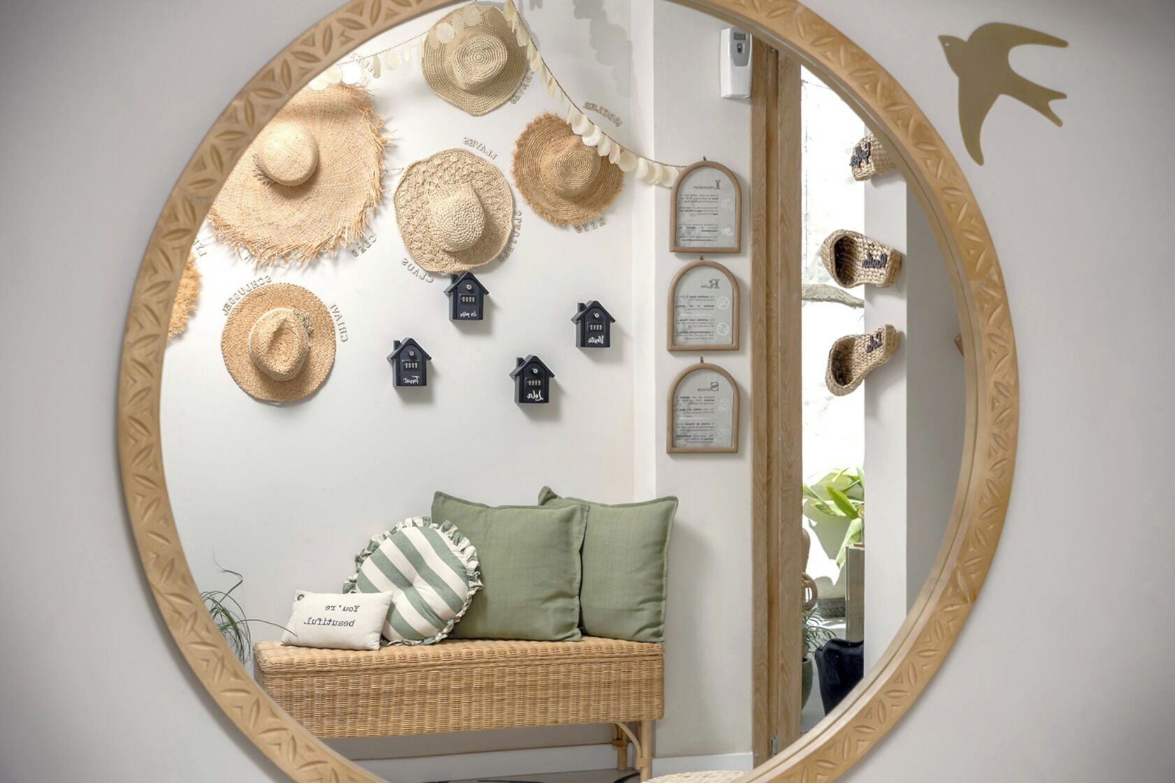 Una habitación con un sofá de mimbre, cojines verdes y un espejo con marco decorativo.