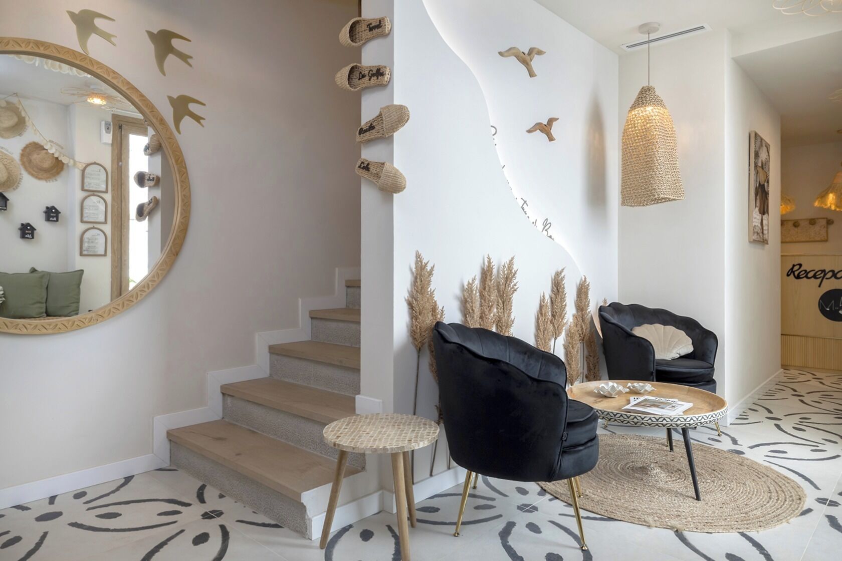 Un interior moderno con una escalera, sillas de terciopelo negro, una mesa redonda y decoración mural.