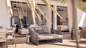 A modern living room with a sofa, chairs, and a dining area. There is a kitchen in the background. - Whales & Waves from Your Terrace • Oceanfront 2BR (Los Cerritos)