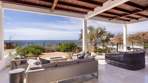 A covered outdoor seating area with a view of the sea, featuring a sofa, chairs, and a small table. - Whales & Waves from Your Terrace • Oceanfront 2BR (Los Cerritos)