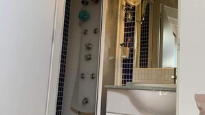 A bathroom with a shower, a sink, and a mirror. - Studio Centro Madrid (Madrid)