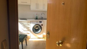 A compact kitchen with a washing machine, a sink, and a small dining area with a bench. - Studio Centro Madrid (Madrid)