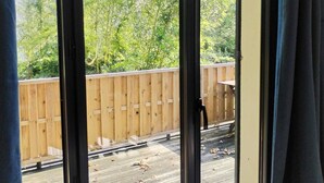 Vista a través de un ventanal grande con una terraza de madera y una valla al fondo.