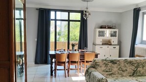 Amplia sala de estar con comedor, sofá, aparador y vista al exterior.