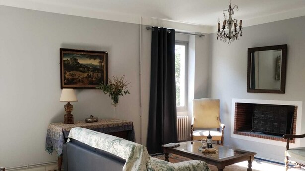 Una sala de estar con sofá, mesa de centro, chimenea, candelabro y un cuadro en la pared.
