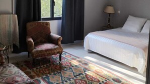 Un dormitorio con una cama, una silla, una lámpara y una alfombra estampada.