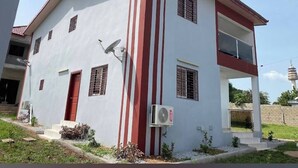 A two-story building with a red and white facade, satellite dish, and air conditioning unit. - Hotel Labertina (Yamoussoukro)