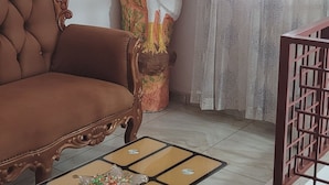 A living room with a brown sofa, a decorative bird sculpture, a glass coffee table, and a window with sheer curtains. - Hotel Labertina (Yamoussoukro)
