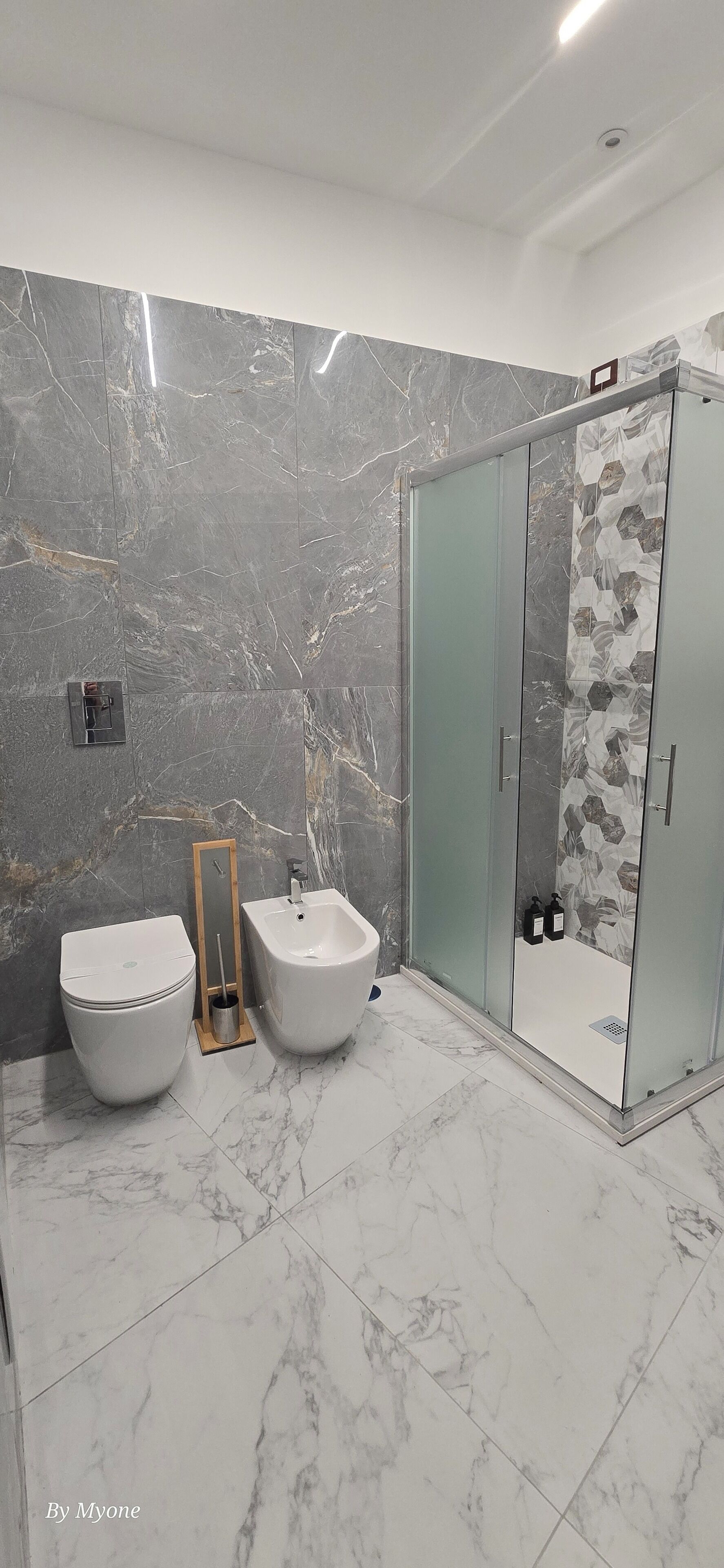 Un baño moderno con inodoro, bidé y ducha con mampara de vidrio.