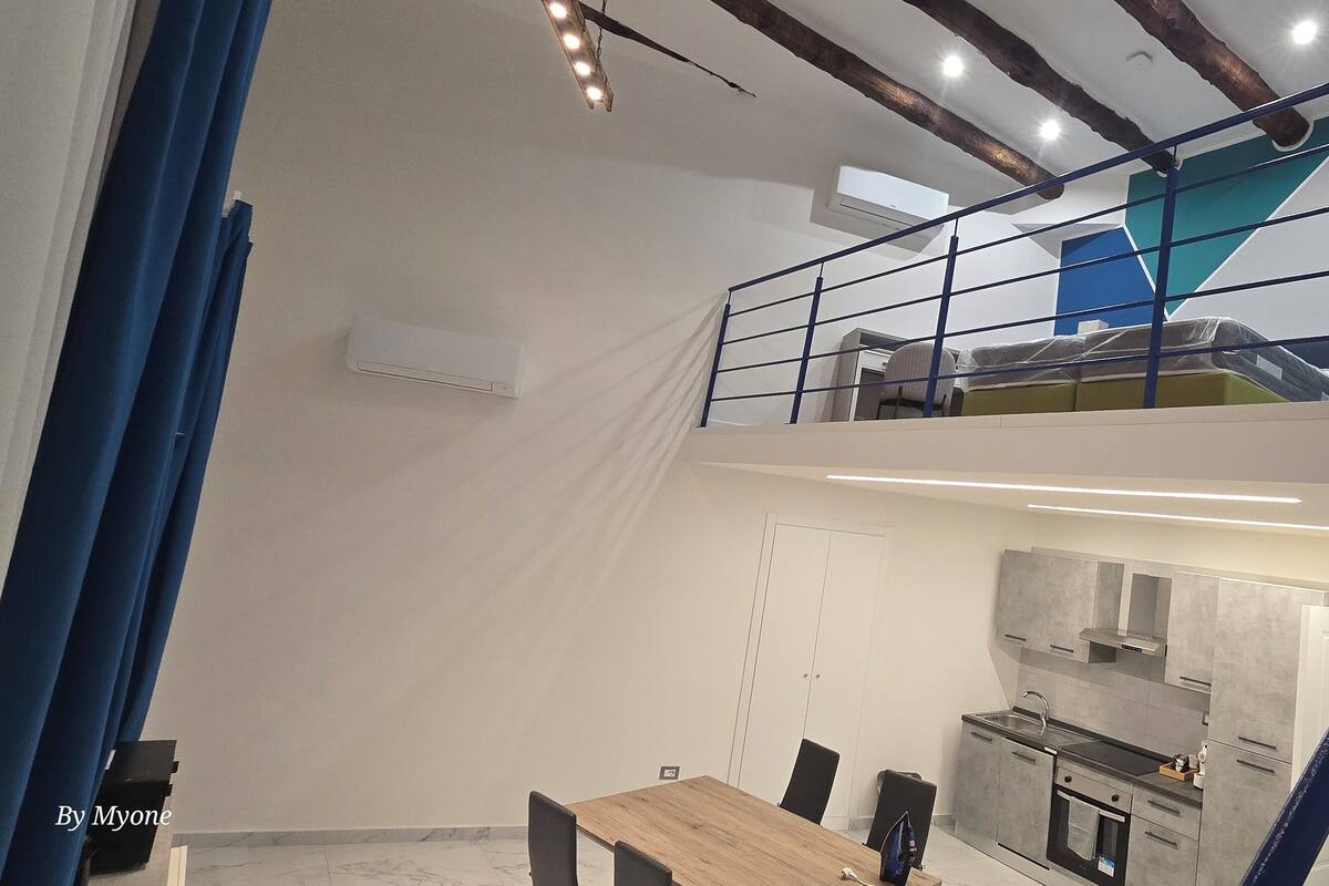 Un appartement moderne de style « loft », comprenant un coin repas, une cuisine et un escalier menant à un niveau supérieur.