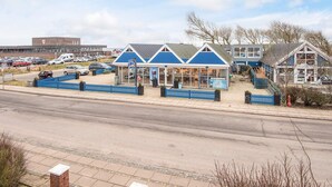 A coastal building with a blue facade, a parking lot, and a clear sky.