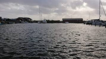 A marina with boats docked, a building with a red roof, and a cloudy sky.