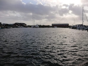 A marina with boats docked, a building with a red roof, and a cloudy sky.