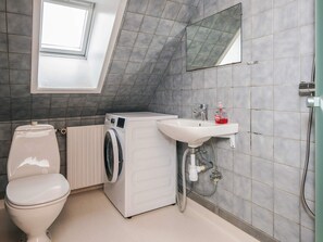 Ein kleines Badezimmer mit Waschmaschine, Toilette, Waschbecken und einem Oberlicht.