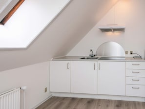 A modern kitchen with white cabinetry, a countertop, and a skylight.