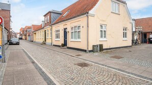 A street with traditional buildings, cobblestone pavement, and a parked car.