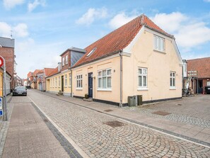 A street with traditional buildings, cobblestone pavement, and a parked car. - 2 Person Holiday Home in Ringkobing (Ringkobing)