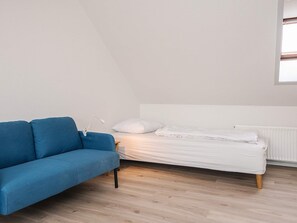 Ein Zimmer mit einem blauen Sofa, einem weißen Bett und einem Fenster.
