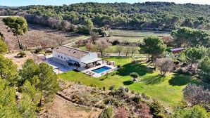 Una casa moderna con piscina, rodeada de un jardín amplio y campos.