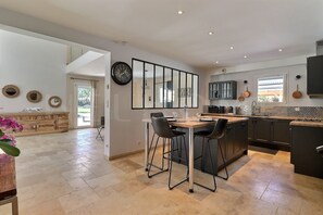 Una cocina moderna con una isla central, taburetes de bar y un comedor.