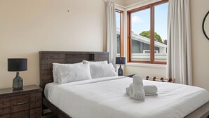 Un lit bien fait, avec du linge de lit blanc, une tête de lit en bois et deux lampes de chevet.