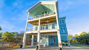 A two-story building with a balcony on the upper floor, a covered entrance, and a surrounding garden. - Amazing Gulf views ~ 4 bedrooms ~ Brand new home ~ Great for families (Cedar Key)
