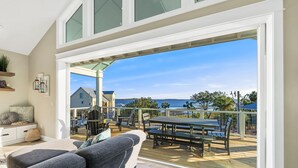 A spacious balcony with a wooden deck, outdoor furniture, and a view of the ocean. - Amazing Gulf views ~ 4 bedrooms ~ Brand new home ~ Great for families (Cedar Key)