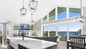 A spacious kitchen with a large island, a dining area with a view, and a living room with a sofa and a TV. - Amazing Gulf views ~ 4 bedrooms ~ Brand new home ~ Great for families (Cedar Key)