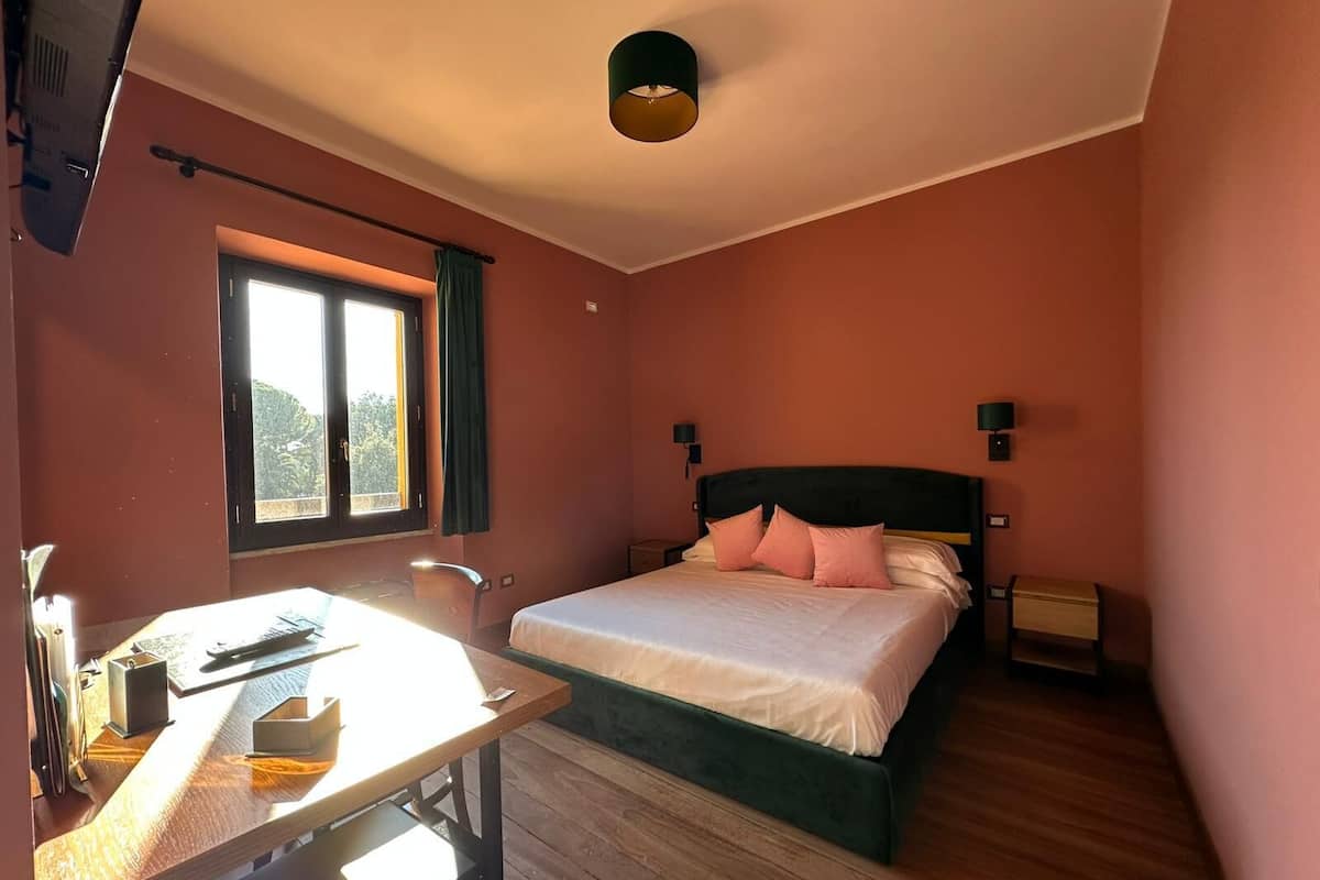 Ein Schlafzimmer mit einem Bett, Nachttischen, einem Schreibtisch und einem Fenster.