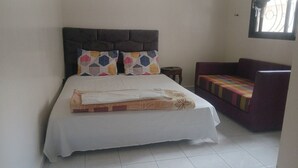 A bedroom with a bed, two pillows, a sofa, and a small table.