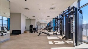 Ein modernes Fitnessstudio mit unterschiedlichen Trainingsgeräten, großen Fenstern und Holzboden.