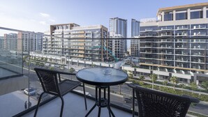 Ein Balkon mit Glastisch und Stühlen, der auf einen Stadtblick mit modernen Gebäuden blickt.