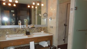 A bathroom with two sinks, a mirror, and a shower.