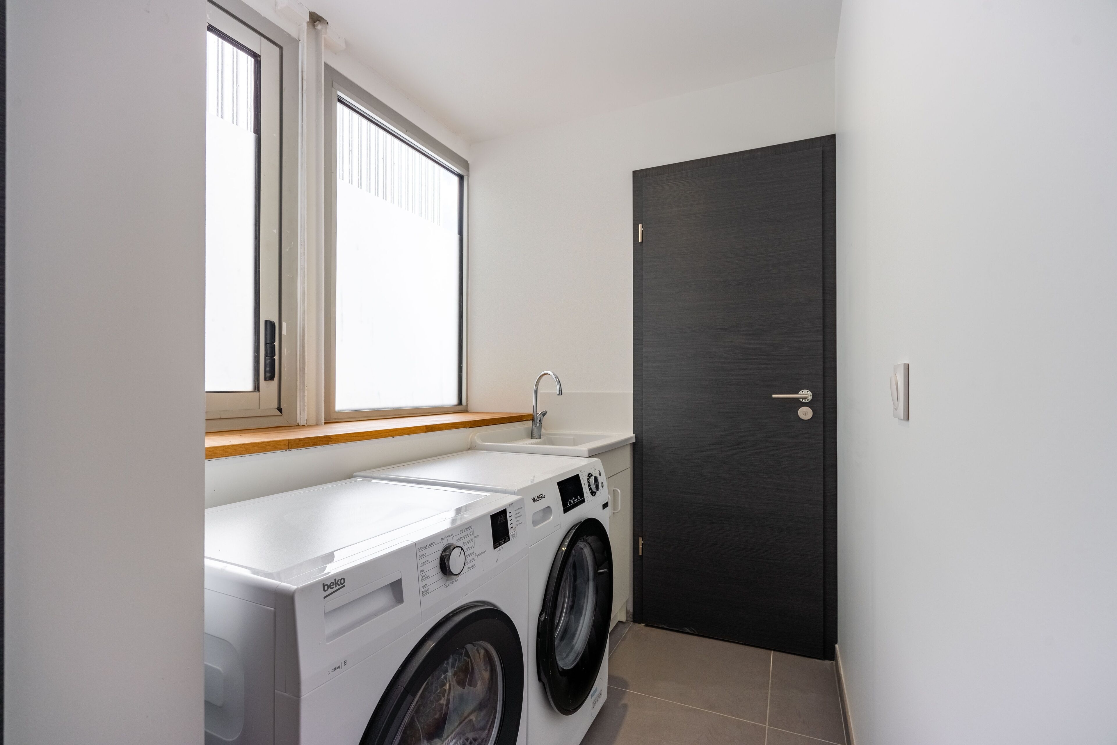 A laundry room with a washing machine, dryer, and sink.