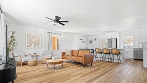 A spacious living room with a wooden floor, a sofa, a coffee table, and a ceiling fan. - 3-bedroom house in by downtown Durham NC (Durham)