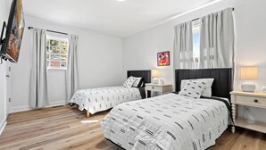 A hotel room with two beds, a TV, a window with curtains, a nightstand, and a lamp. - 3-bedroom house in by downtown Durham NC (Durham)