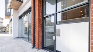 Ein modernes Gebäude mit großen Glasfenstern, einer Ziegelsteinsäule und einem Schild mit der Aufschrift 'Stanley Road Arts 41-60'.
