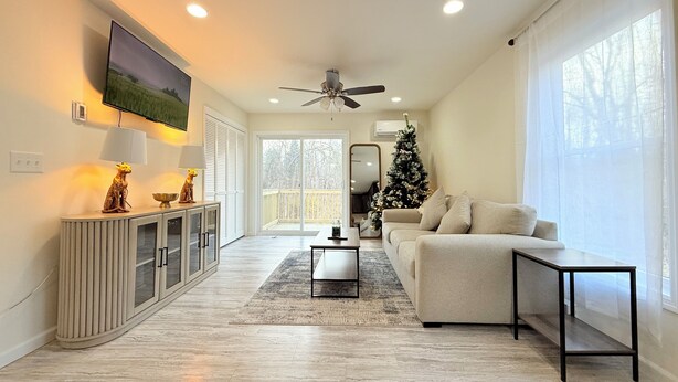 A modern living room with a flat-screen TV, a ceiling fan, a Christmas tree, a sofa, and a coffee table.