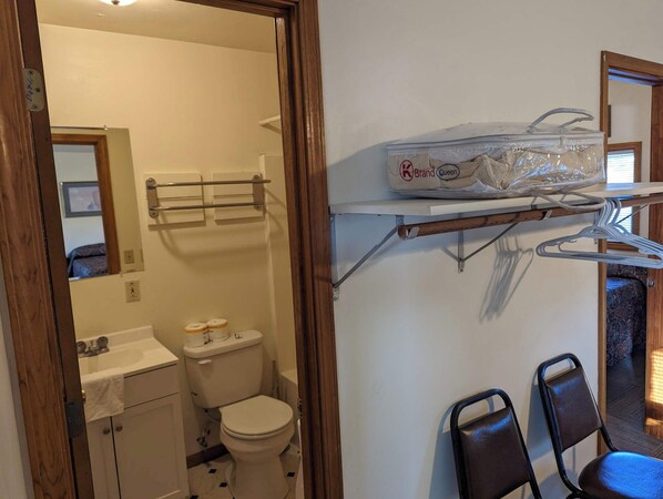 A bathroom with a toilet, sink, and a shelf with a plastic bag. - Family Cabin by a private fishing lake (Perry)
